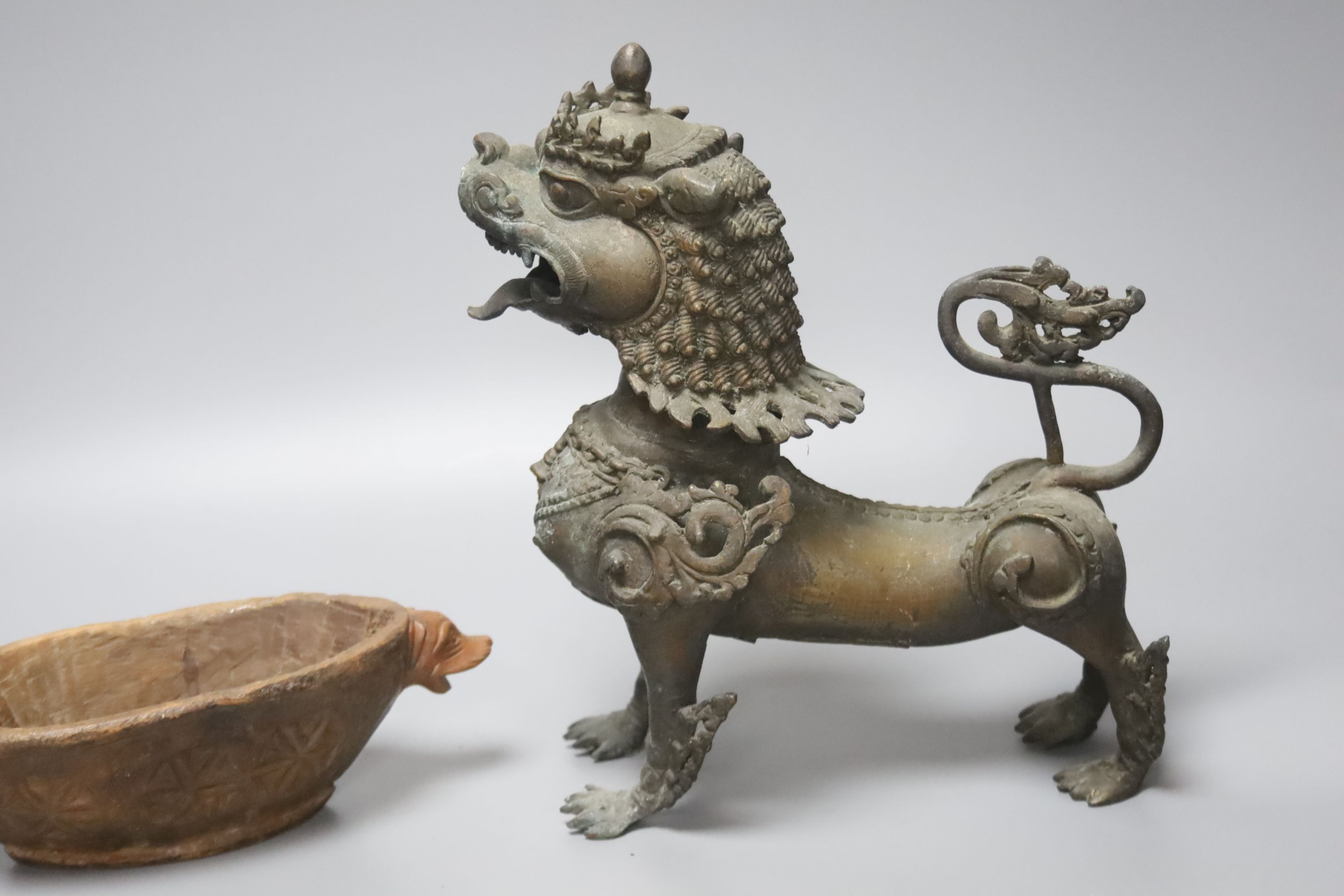 A South East Asian brass Buddhistic lion, carved wood vessel and an African tribal beaded pouch